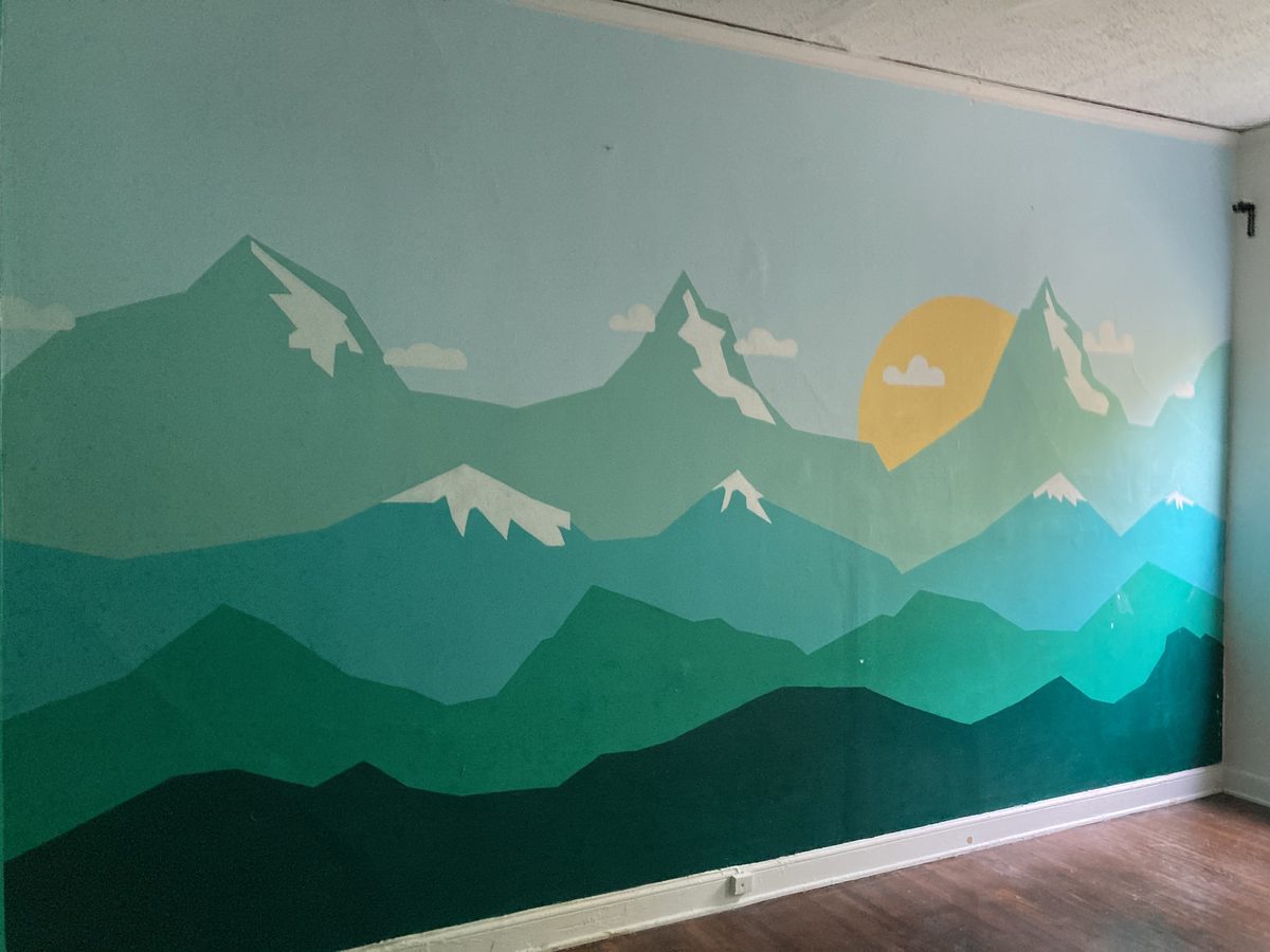 Mountain landscape mural with layered greens and sun